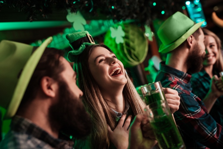 A group of people at a St. Patricks Day themed party, drinking and smiling.