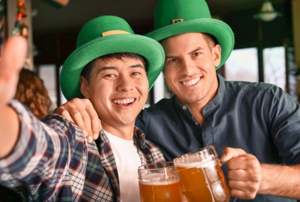 Two men with beer posing for a photo on St. Patricks Day.