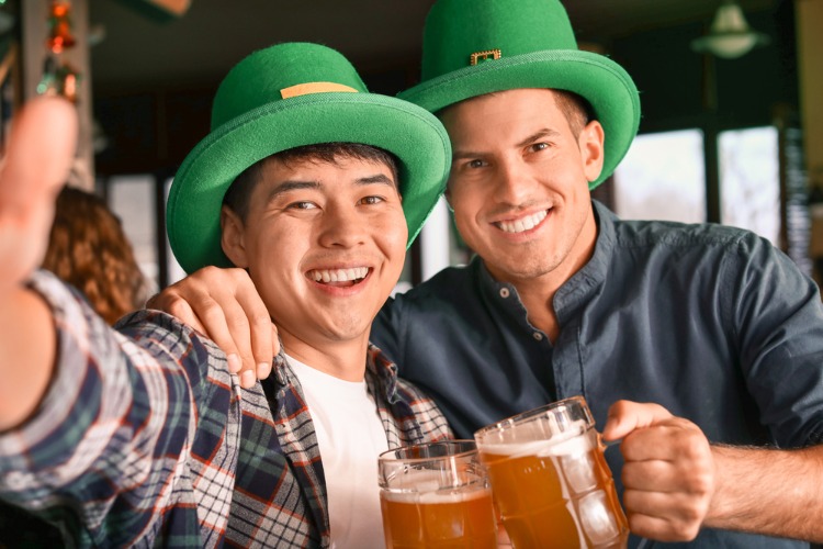 Two men with beer posing for a photo on St. Patricks Day.