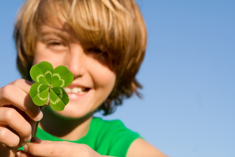 A kid with a four-leafed clover smiling.