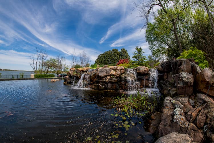 small rocks, a pond, and small waterfalls at the dallas arboretum on a sunny day