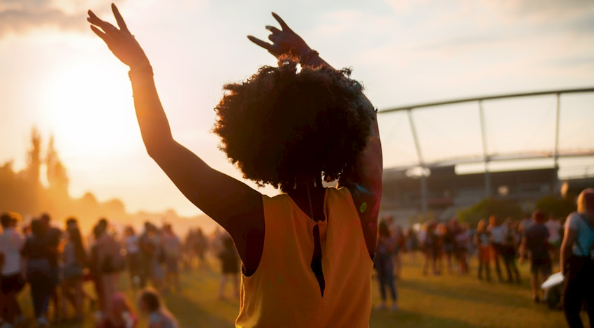 a woman dances with her arms up at an outdoor theater performance in Houston, Texas