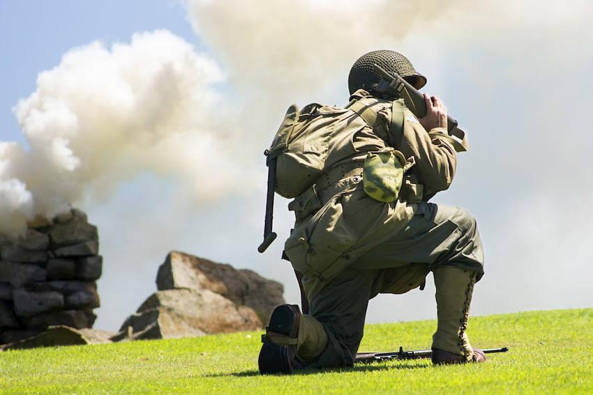 A solidier in a battle scene, communicating over the phone.