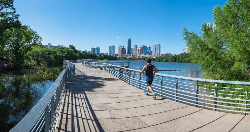 a jogger runs by on the boardwalk overlooking Lady Bird Lake in Austin