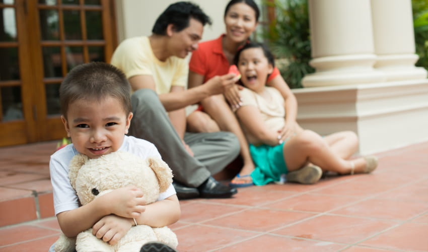 a child with a teddy bear sits on the steps of a mansion