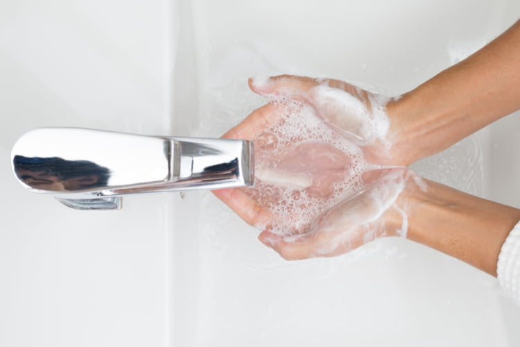 someone washes their hands using a sink