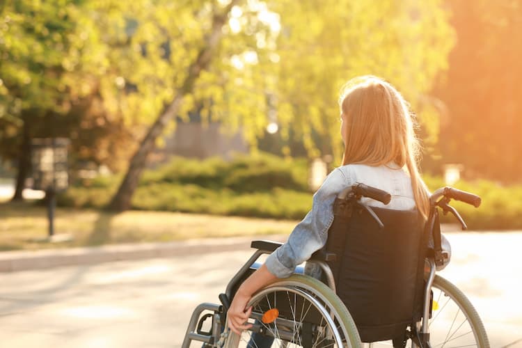 Teenage girl using wheelchair outdoors