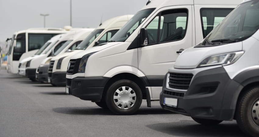 A lineup of parked white minibuses in a parking lot