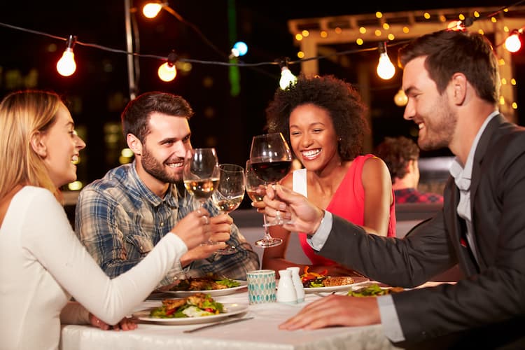 Friends having dinner on rooftop at night