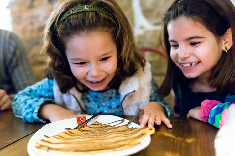 Two young girls smiling over crepe