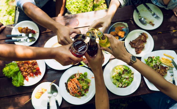 friends cheers their drinks over a table full of food