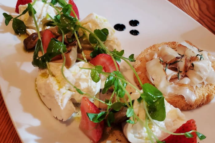 small toasted bread with soft cheese and greens on top