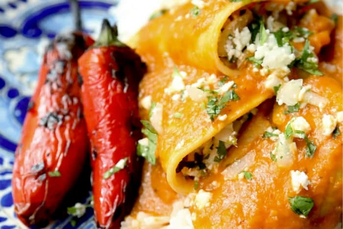 a closeup of corn tortillas with cheese and cilantro and two charred peppers