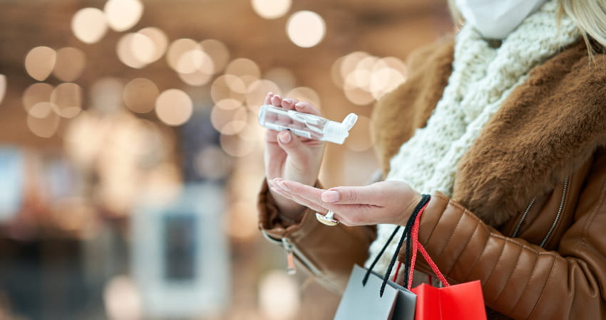A woman sanitizes her hands while holiday shopping