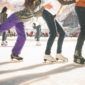 A line of ice skaters holding each others hips as they skate