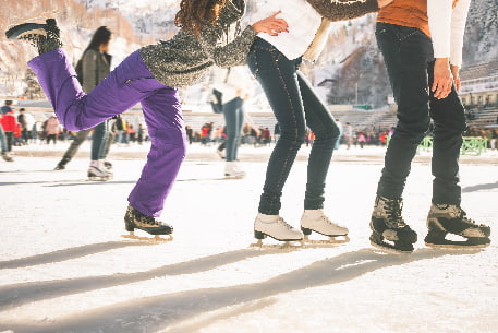 A line of ice skaters holding each others hips as they skate