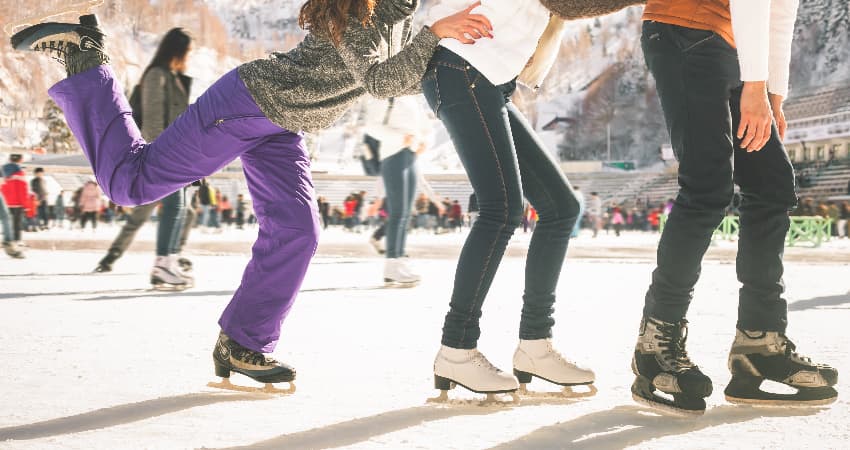 A line of ice skaters holding each others hips as they skate