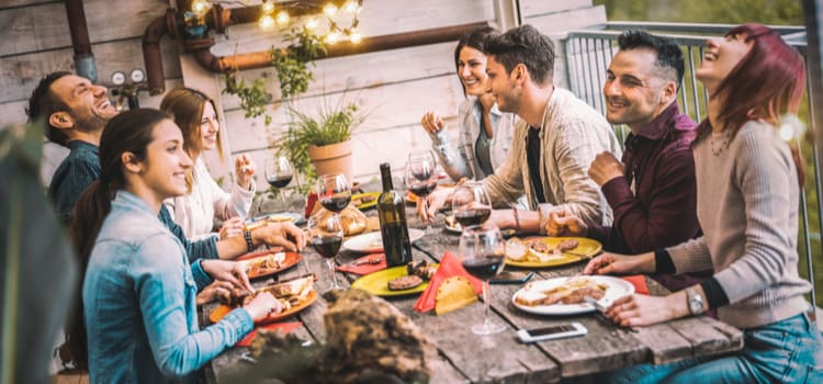 friends sit around a table and laugh while enjoying a barbecue meal