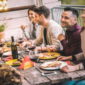 friends sit around a table and laugh while enjoying a barbecue meal