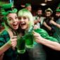 Two girls in a wig and a cap in a bar celebrate St. Patrick's Day.