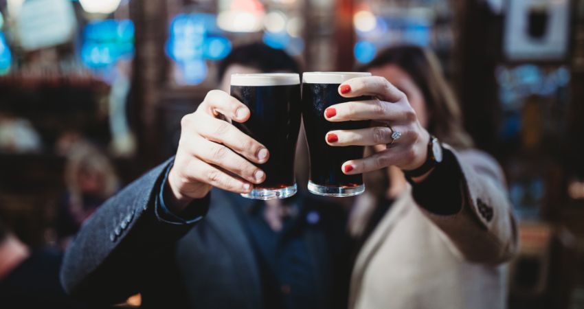 a couple clinking together glasses of dark stour beer